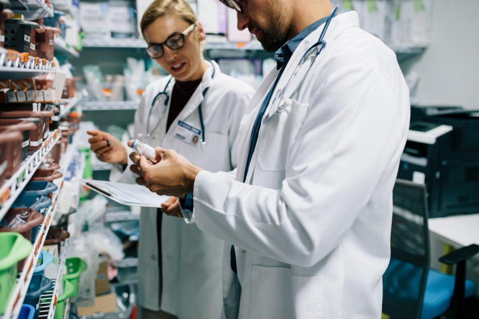 Two businessmen look at the vial.